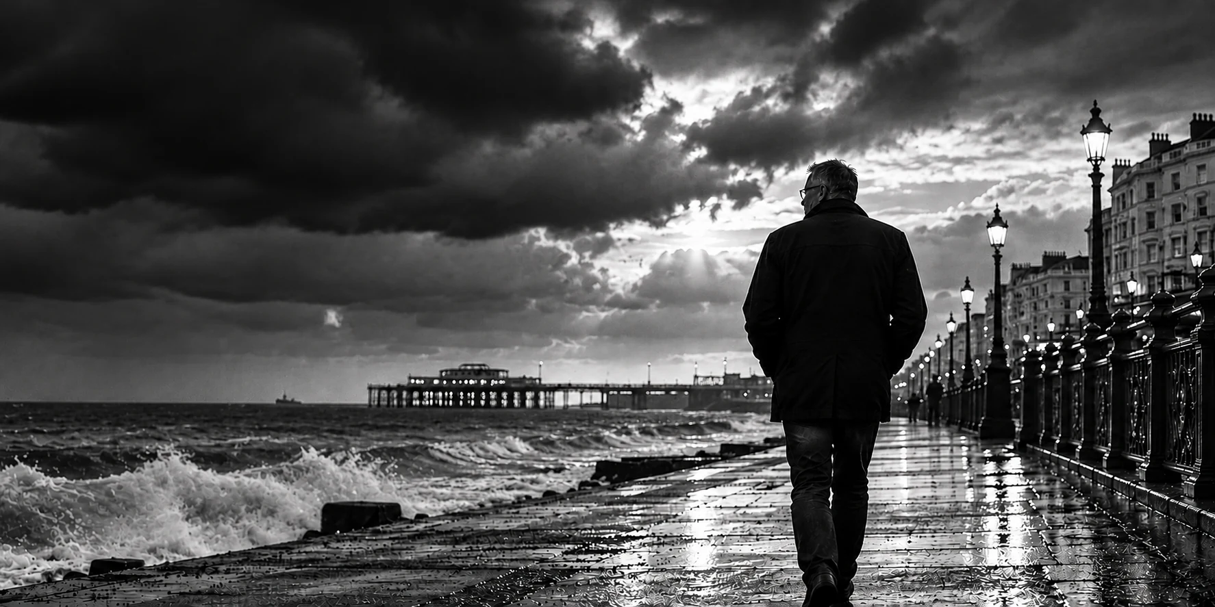 Black-and-white seaside promenade beneath dramatic clouds